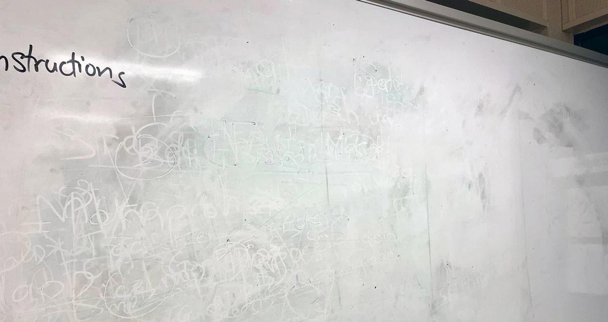 Quadro branco manchado, com a sombra do que esteve escrito a não sair da superfície